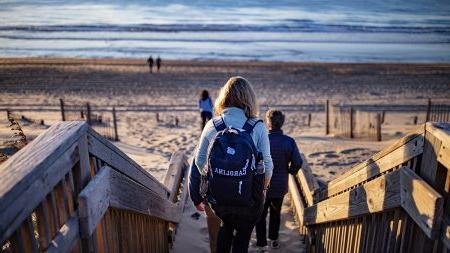 人 walking down a pier on a beach