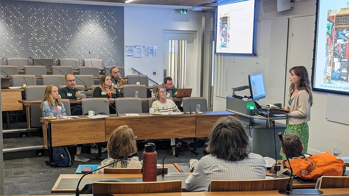 A presenter speaking to adults in a college classroom.